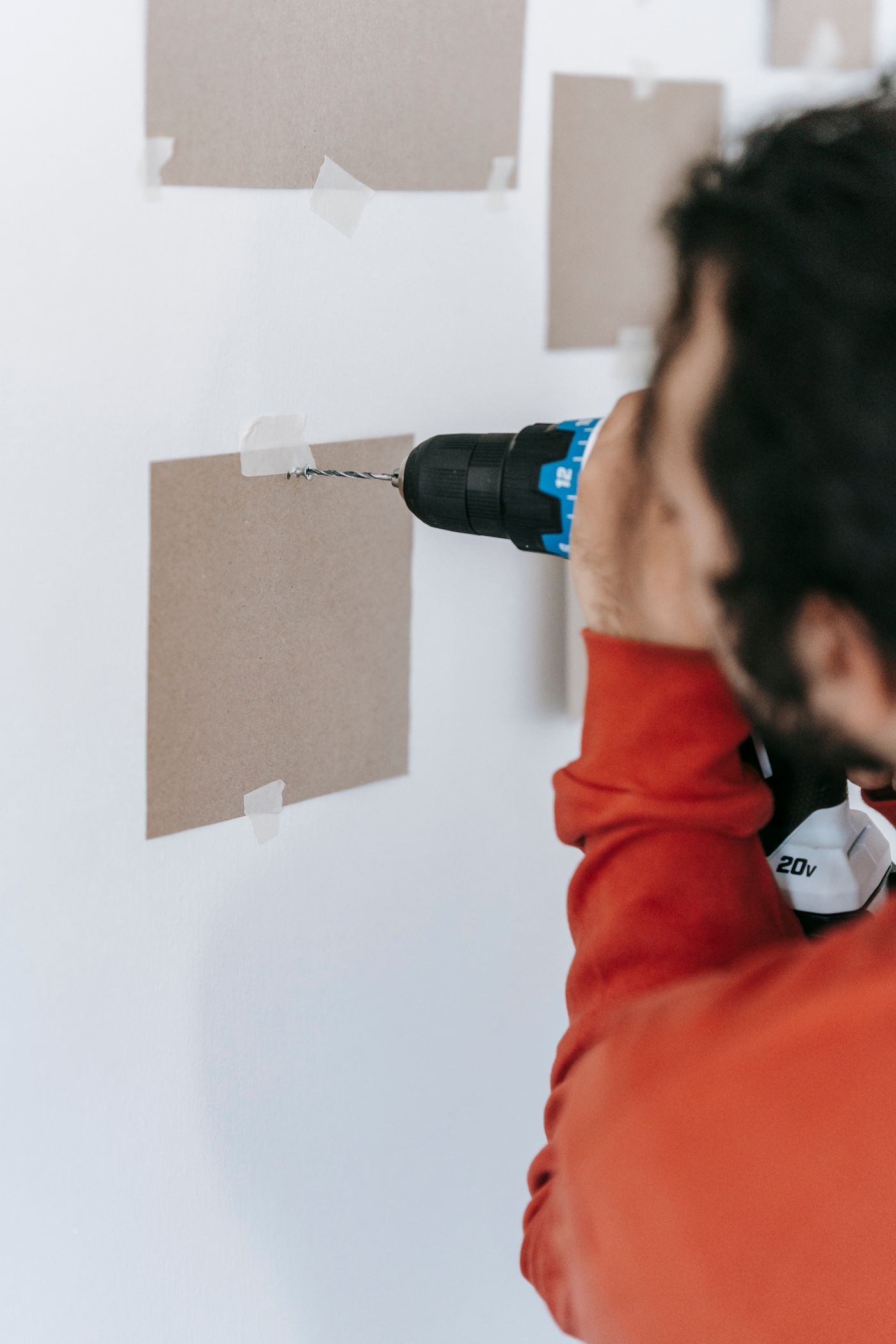 Representative stock photo of a person drilling into an interior wall for repair work