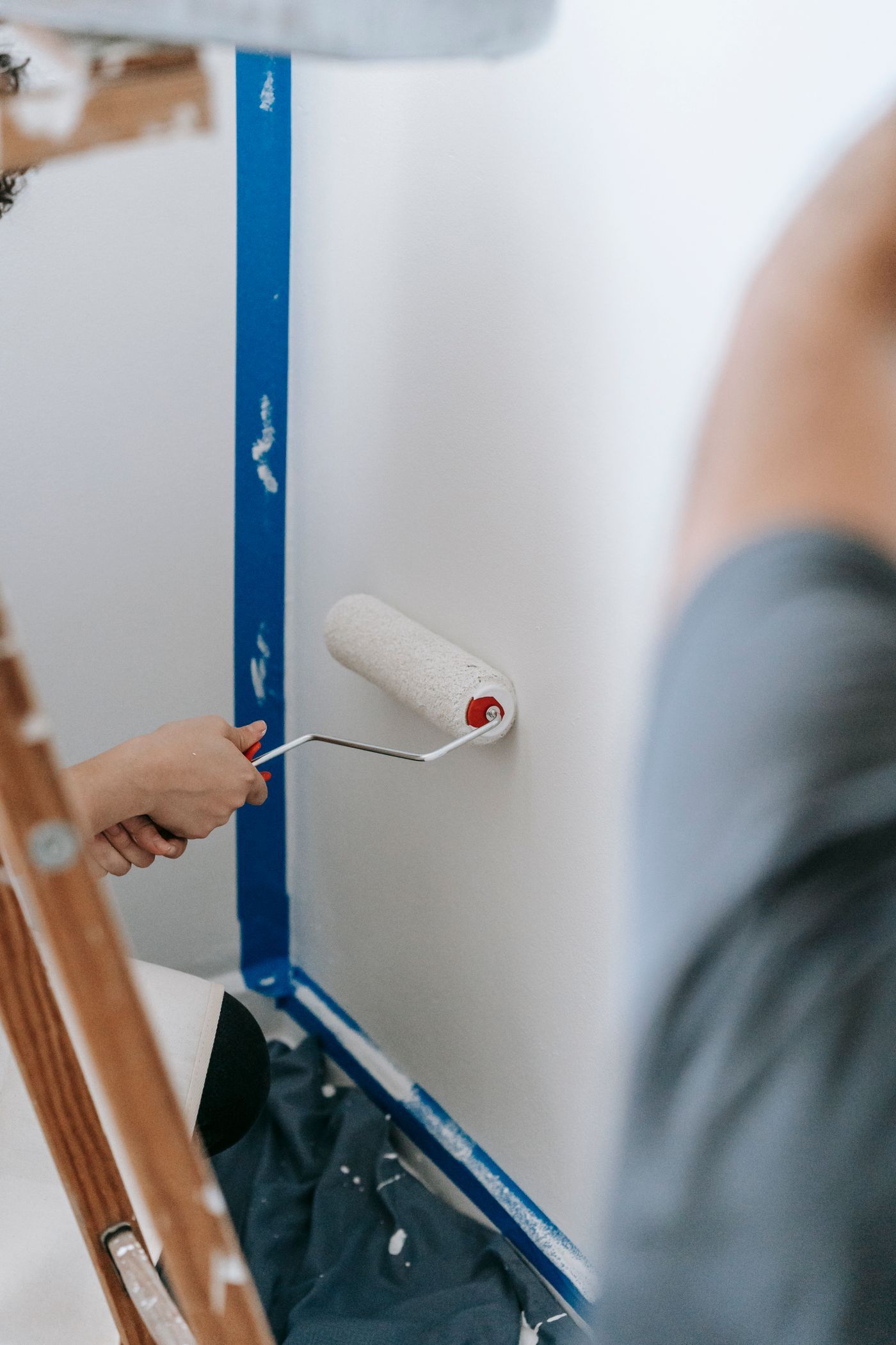 Representative stock photo of people painting an interior wall with rollers